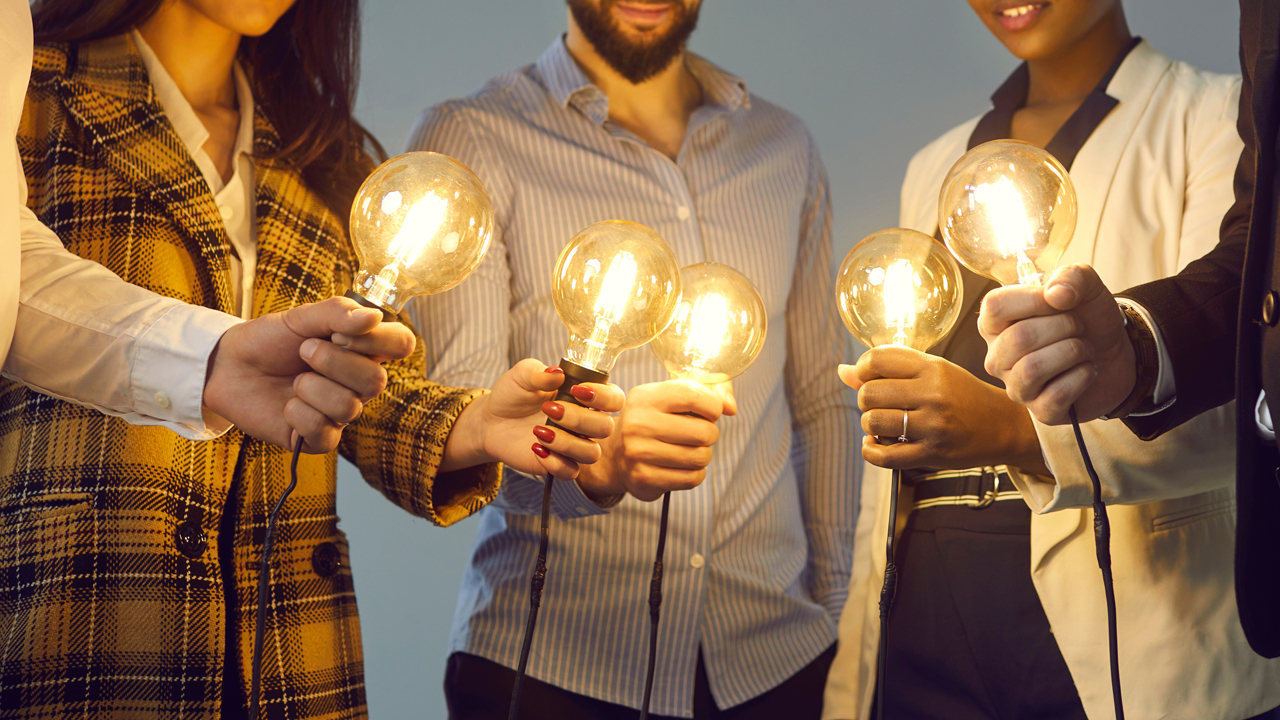 Five people in a circle holding light bulbes