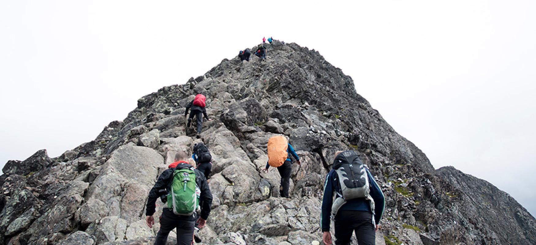 People hiking up a rocky mountain top.