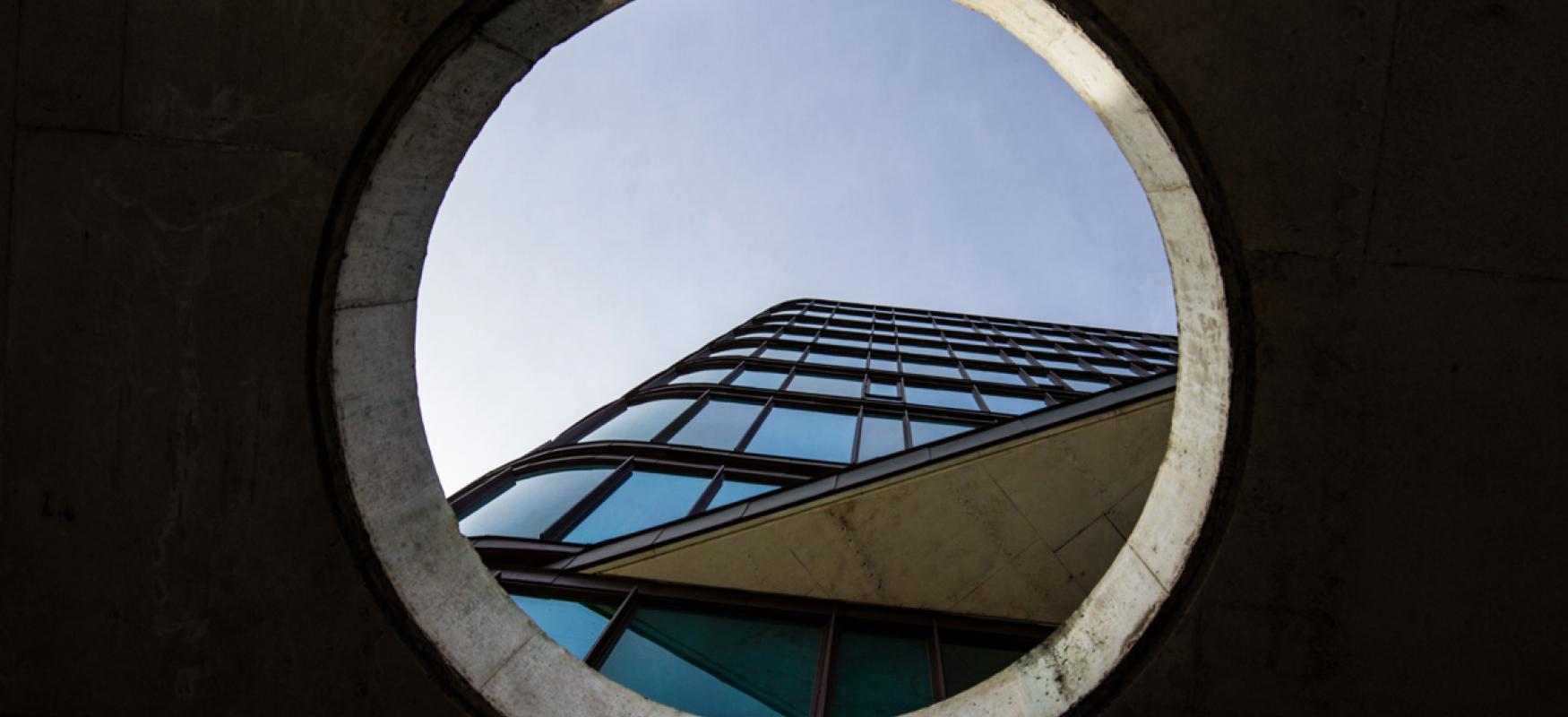 Building in Copenhagen seen through a circular hole in a concrete wall.