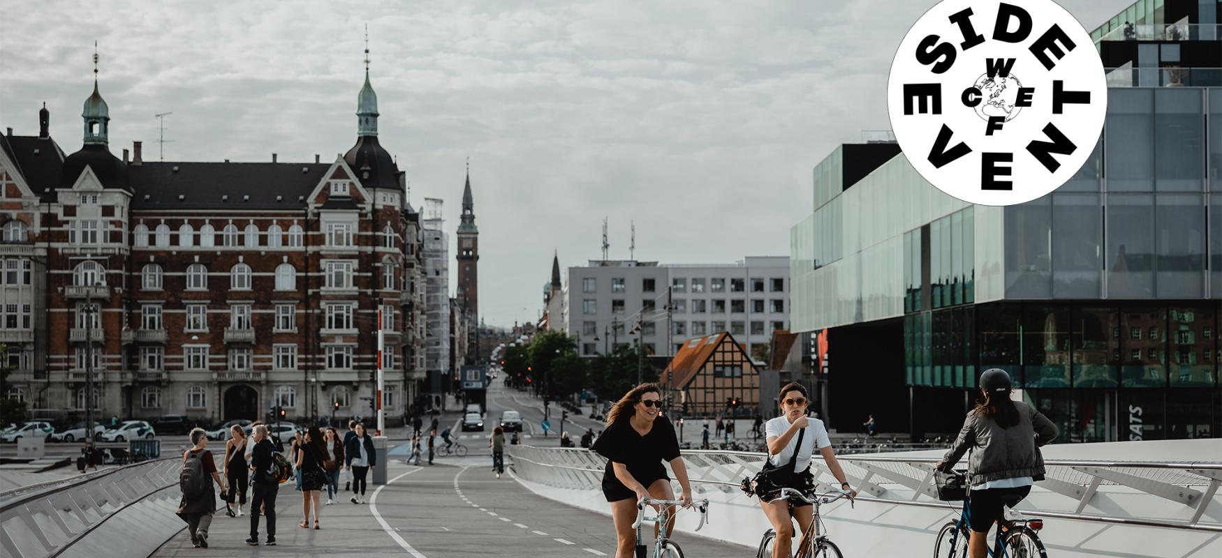Two women driving their bikes across a bridge in Copenhagen.
