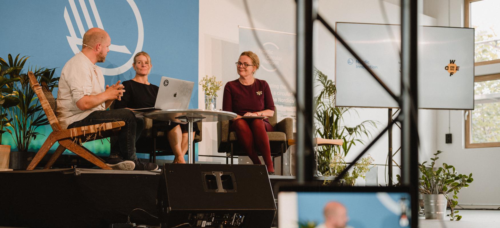 WCEF2021 a computer placed on the floor, mirroring the background where three people a carrying out a webinar.
