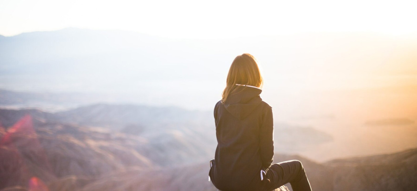 Woman sitting on top of a mountain looking at the landscape 