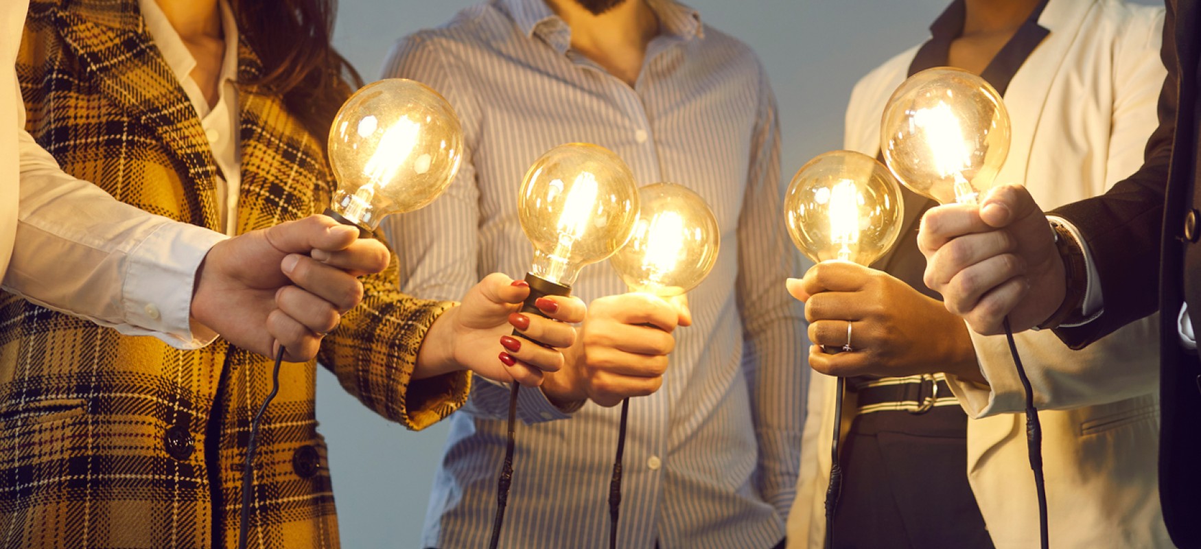 Five people in a circle holding light bulbes
