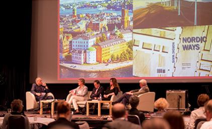People sitting on stage in front of a presentation screen.