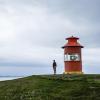 Man, standing beside lighthouse, looking at the sea in Iceland