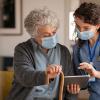 Elderly woman and nurse looking at a tablet