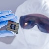 Person wearing lab gear holding up a semiconductor chip